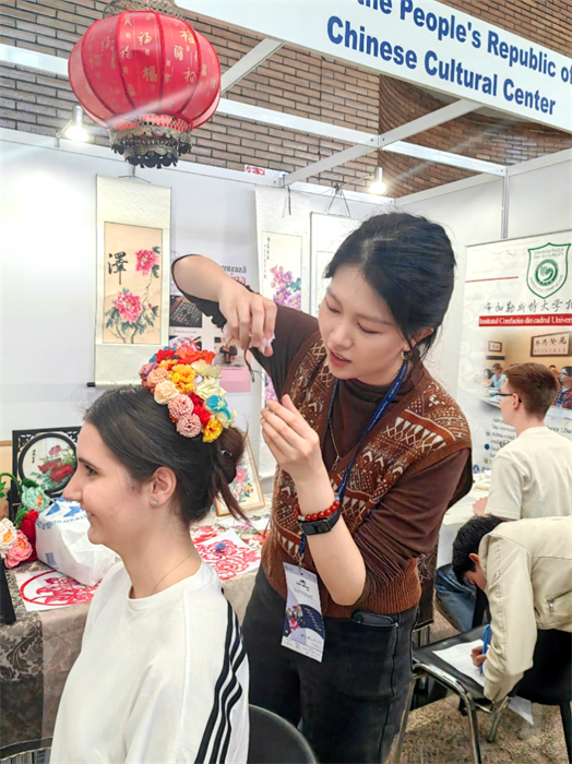 展覽正值羅馬尼亞迎春花節(jié)，國際中文教師志愿者潘婧穎向游客們介紹了國家非物質(zhì)文化遺產(chǎn)——福建泉州的簪花文化。布加勒斯特大學(xué)孔子學(xué)院供圖。
