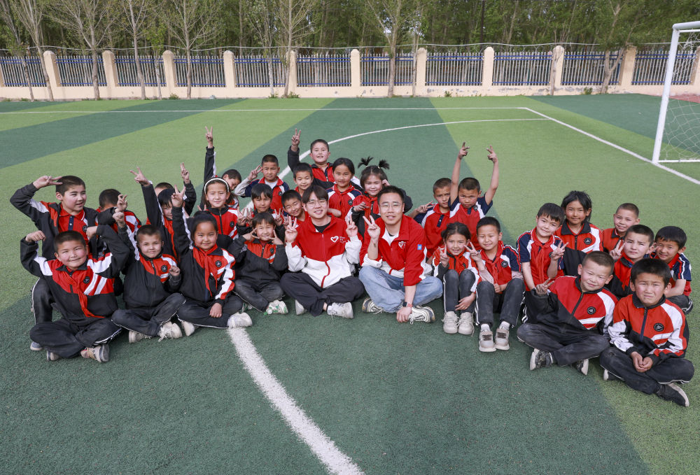 4月23日，在新疆克州阿圖什市哈拉峻鄉(xiāng)謝依特小學(xué)，支教教師王俊文（中左）、李軻凡（中右）和學(xué)生在一起。